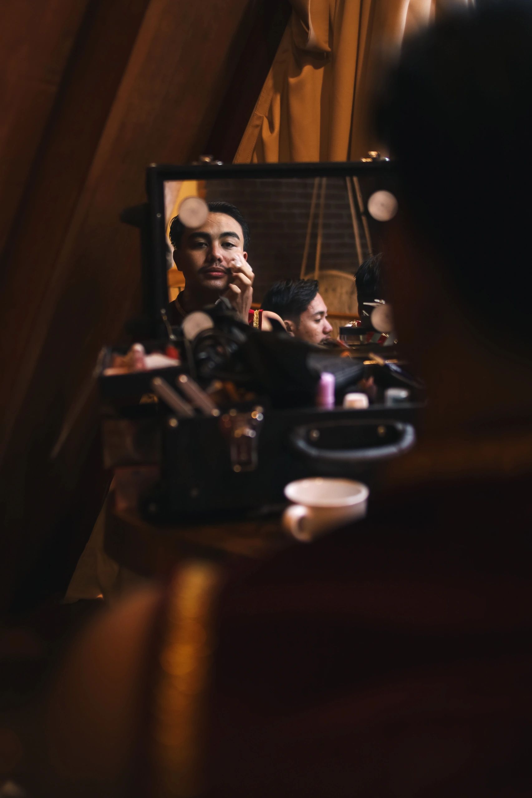 Artista revisando maquillaje frente al espejo en backstage